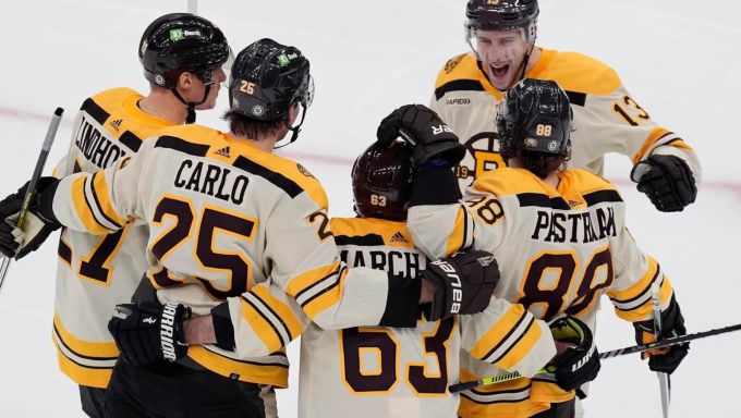 Boston Bruins players surrounding Brad Marchand after scoring