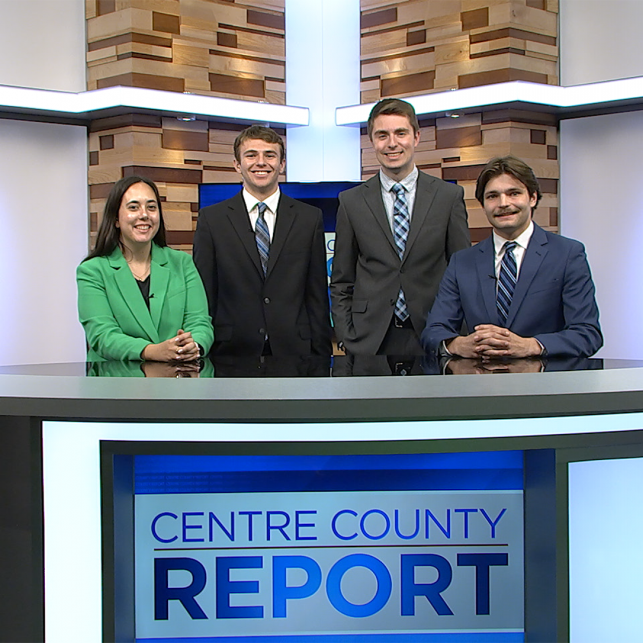 Four Centre County Report anchors standing behind the Centre County Report anchor desk