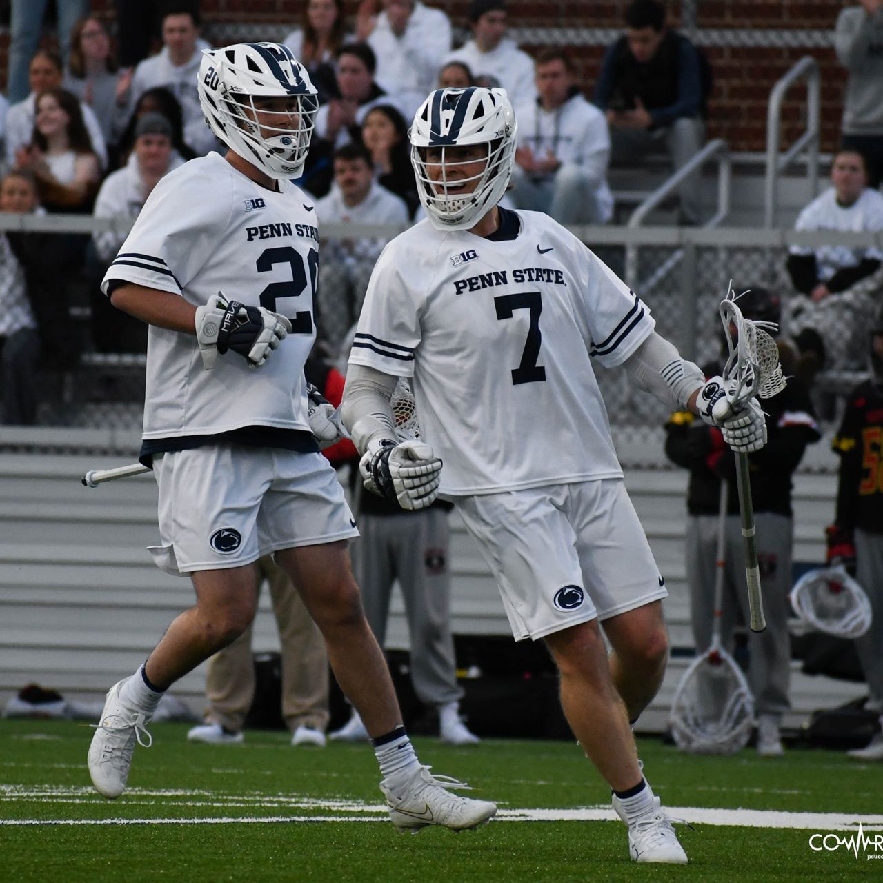 A lacrosse player in a white uniform celebrates a goal