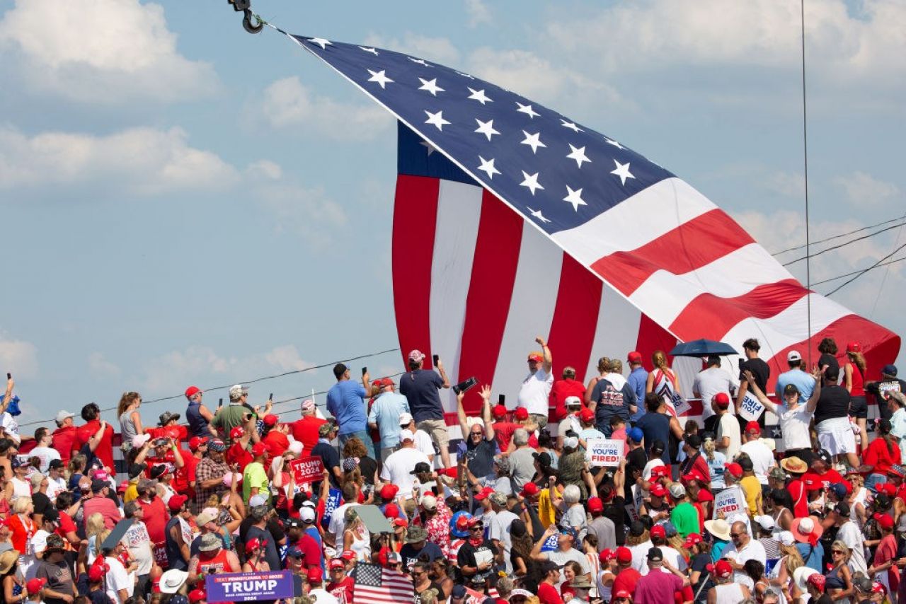 A crowd of people looks at a U.S. flag