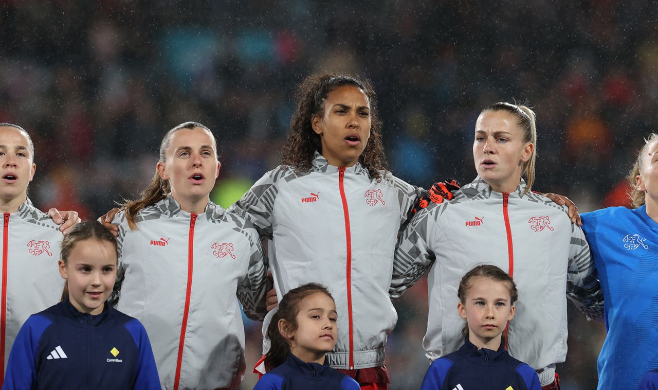 Soccer players stand for the national anthem