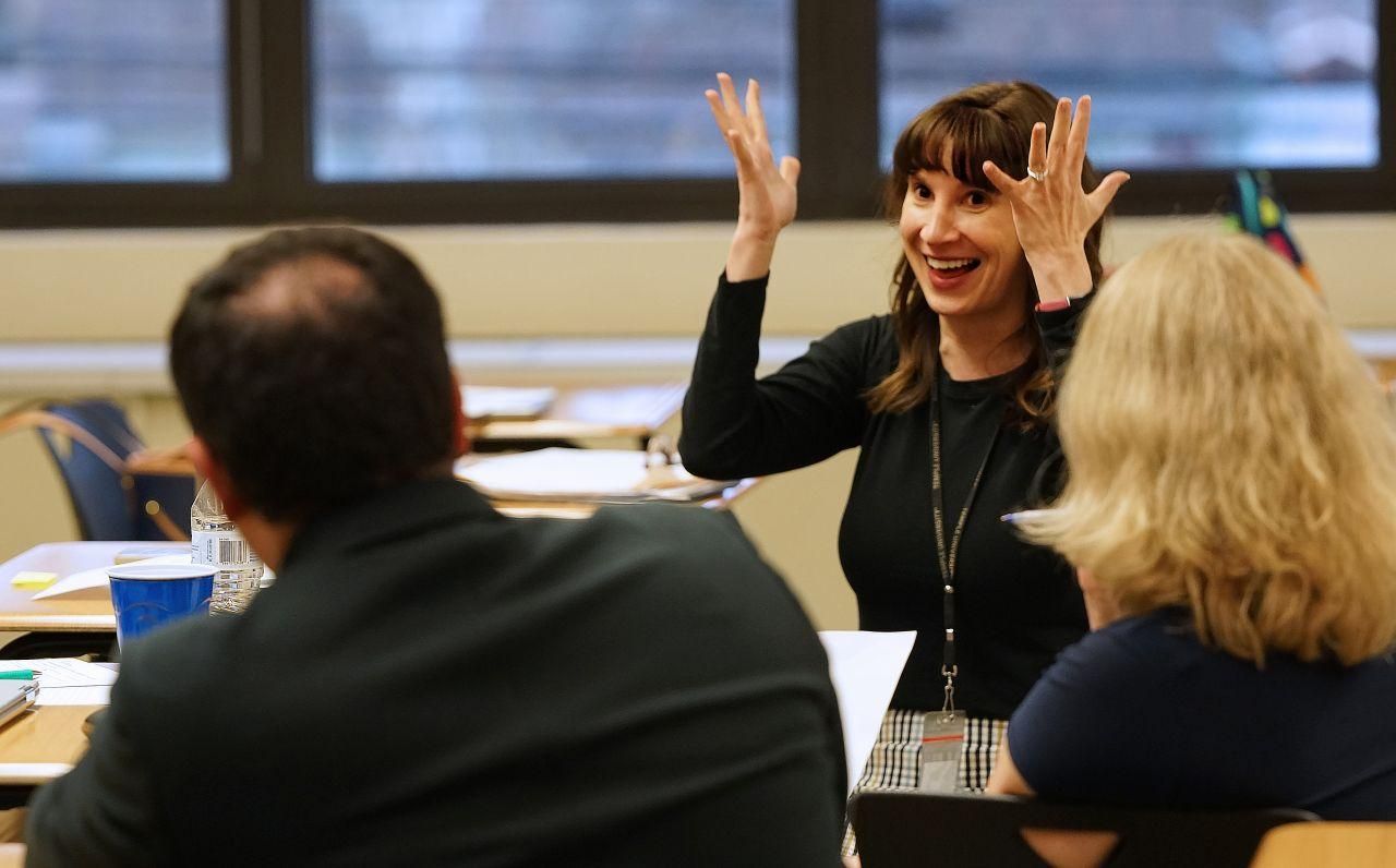 A happy teacher raises her hands while excitedly making a point