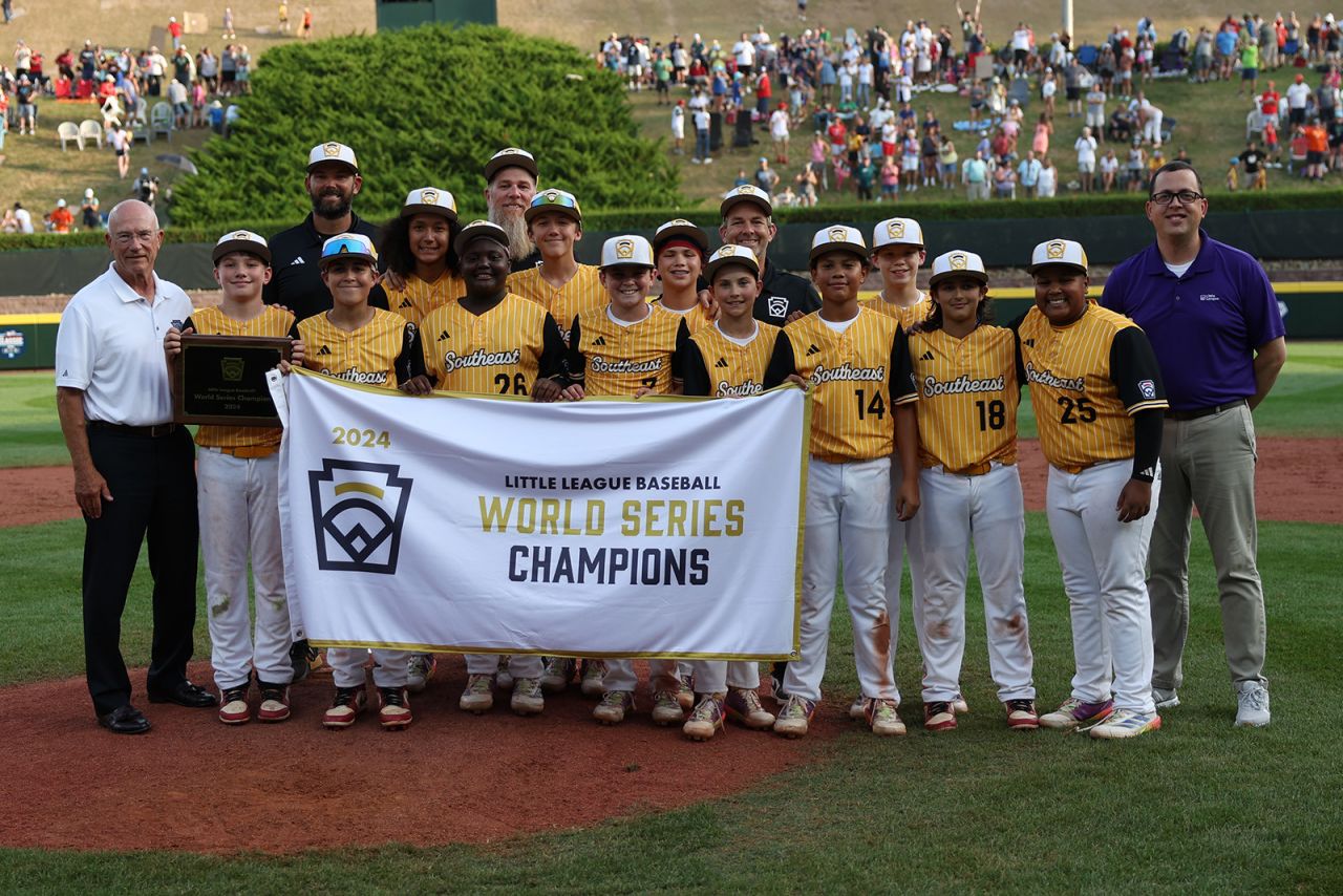 Baseball team stands to pose with banner