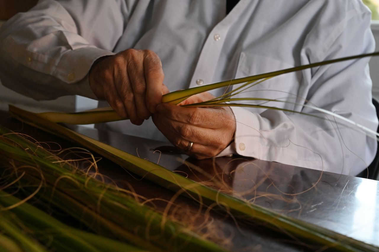 A close up of a man separating palm branches.
