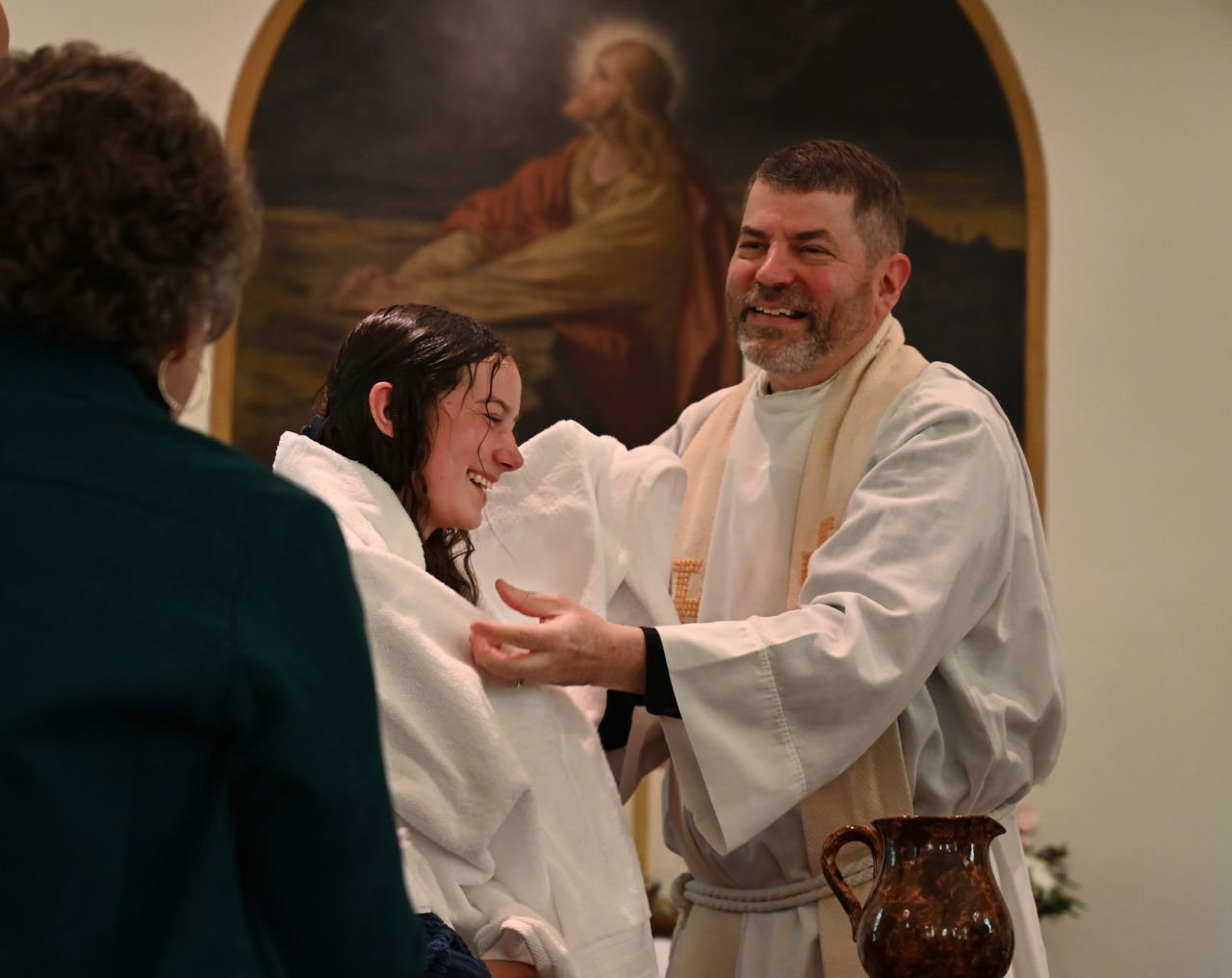 A dark-haired man prepares to hug a woman after her baptism.