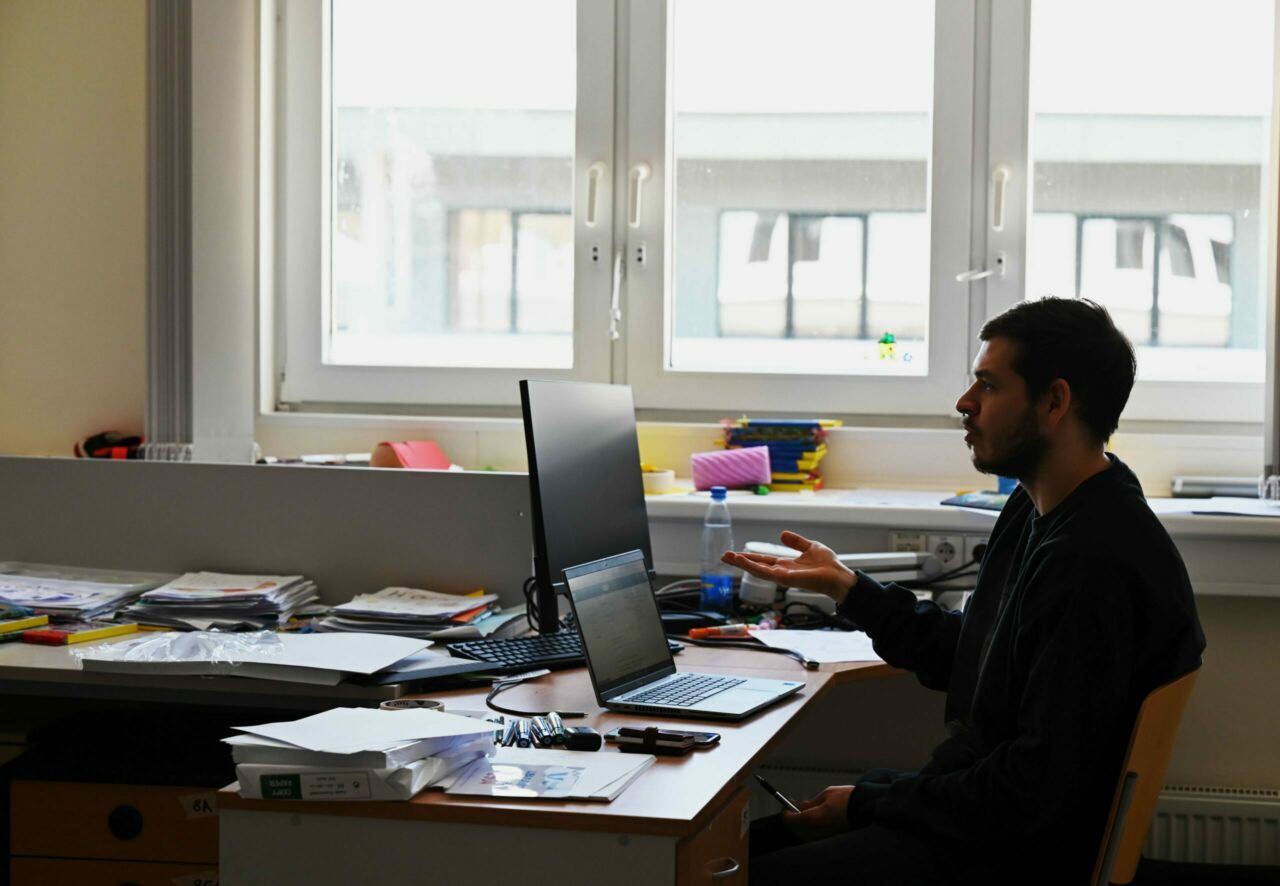 A man sits partially in shadow at a desk