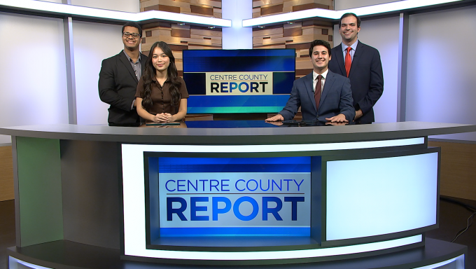 four news centre county report anchor standing behind a news desk