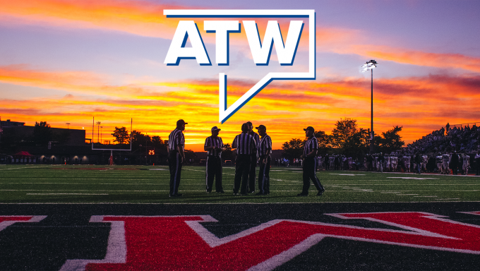 sunset over a football field with referees in the foreground