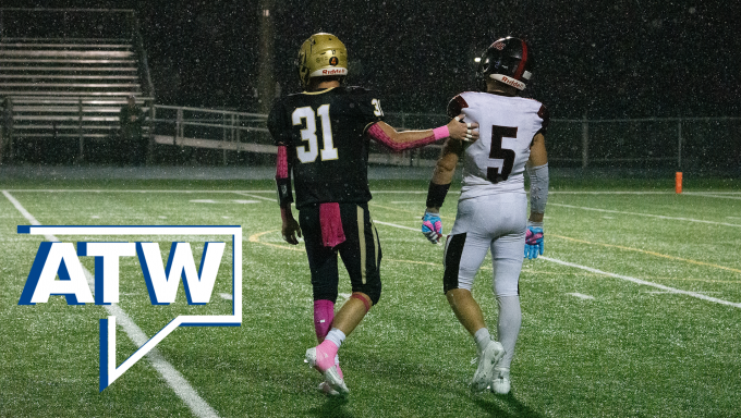 two high school football players walking with the arms around each other