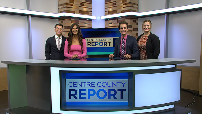 Four Centre County Report anchors standing behind an anchor desk in a studio