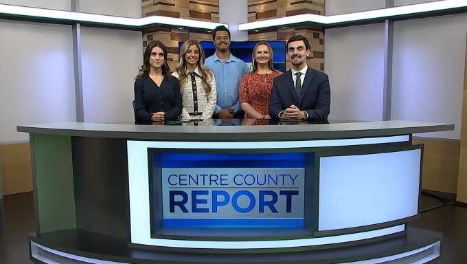 Five Centre County Report news anchors and reporters standing behind the Centre County Report anchor desk