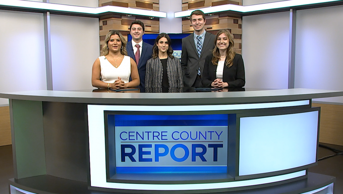 Five Centre County Report anchors and reporters standing behind the Centre County Report anchor desk