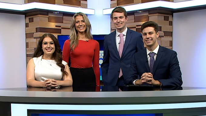 Four Centre County Report anchors standing behind the Centre County Report desk