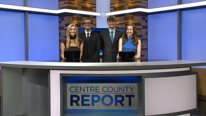 Four television anchors standing behind an anchor desk