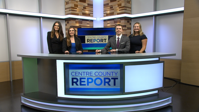 Four Centre County Report anchors standing behind an anchor desk.