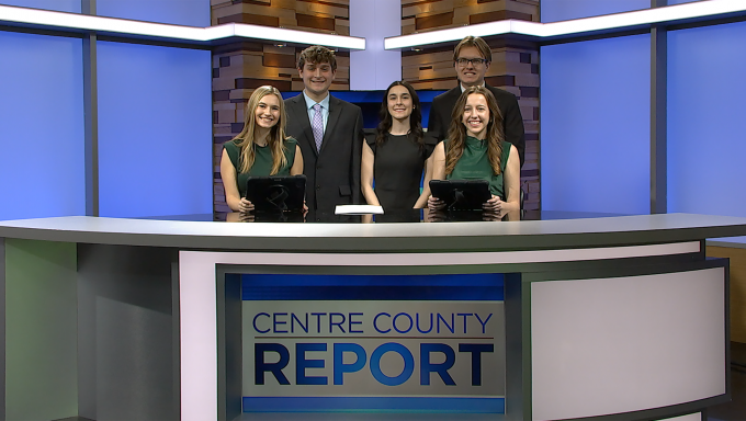 four reporters standing behind an anchor desk