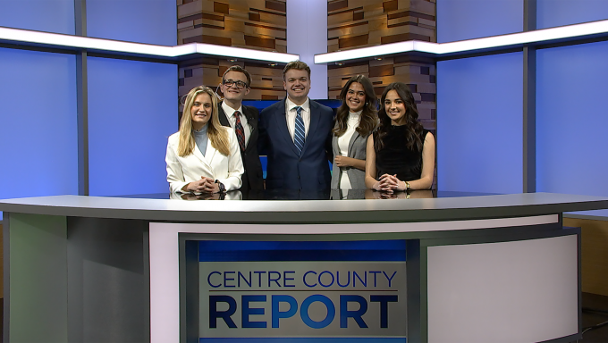 five young reporters and anchors standing behind an anchor desk