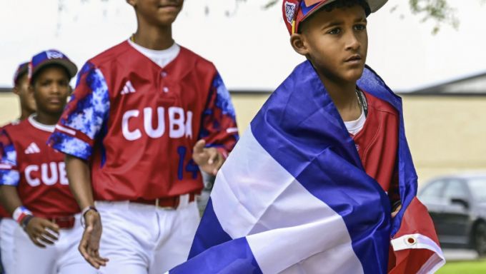 Little League player walks with a flag draped over his shoulders