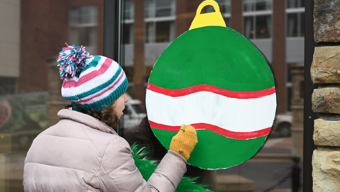 Let's Face It with Emily paints an ornament on the glass.