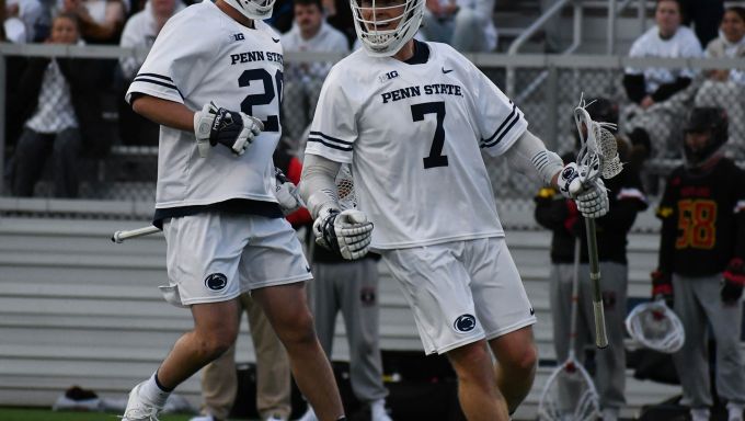 A lacrosse player in a white uniform celebrates a goal