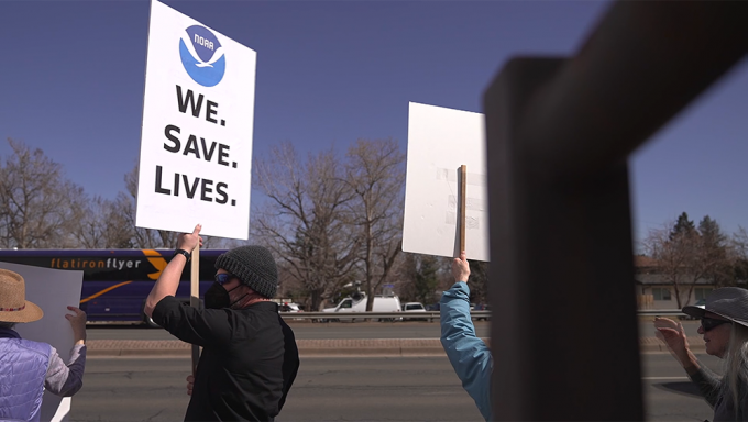 Protesters rally for the National Oceanic and Atmospheric Administration. "We Protect Lives," the sign says.