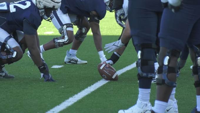 Penn State offensive and defensive linemen line up with a football for a practice snap.