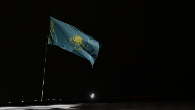 Flag of Kazakhstan on top of a building in Almaty at night