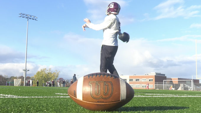 State High Quarterback on the practice field with a football in the foreground