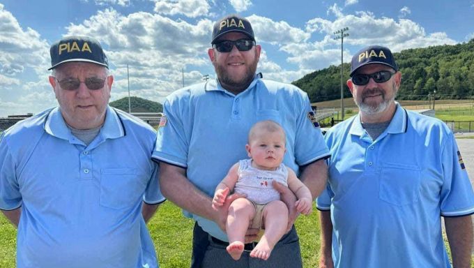 The three Umpires in the family pose for a picture after the game with Alex holding his son Everett