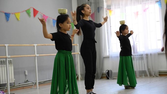 A Uyghur dance instructor teaching two young Uyghur girls how to perform a traditional dance