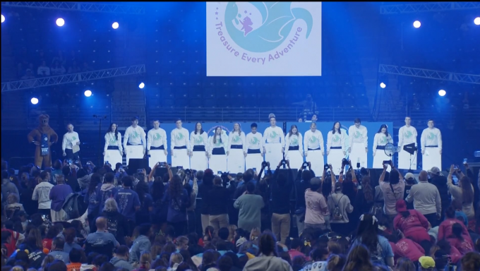 Students onstage at Penn State's Dance Marathon prepare to raise placards above their heads with numbers written on them to reveal the total amount of money raised from 2024's event which benefits children with cancer and their families in various ways.