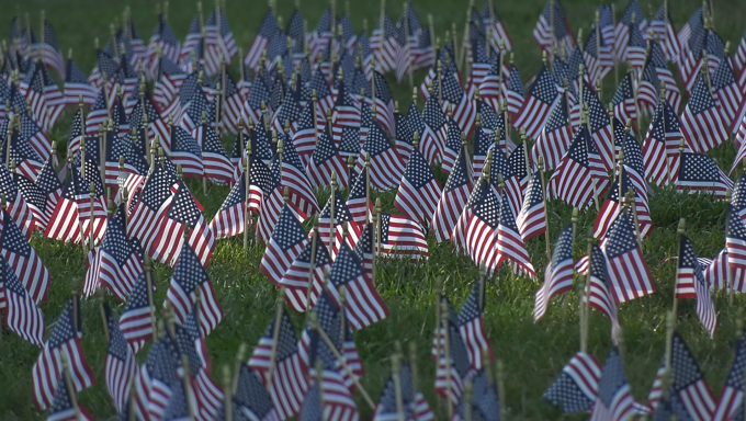 Small American flags planted in a field to commemorate the lives lost on the 9/11 attacks.