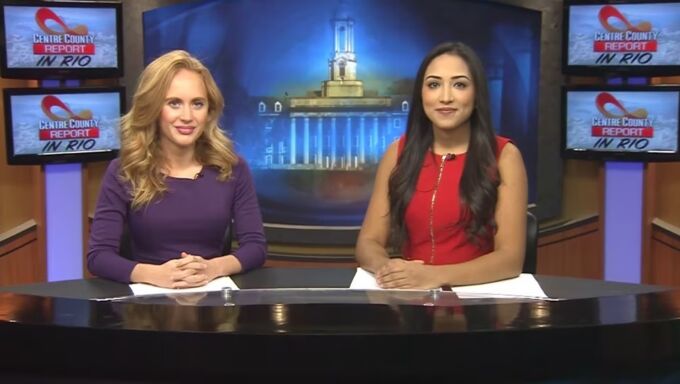 Two female student news anchors sit behind a news desk. Monitors in the background read Rio 2016