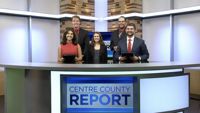 Five Centre County Report anchors and reporters standing behind the Centre County Report anchor desk