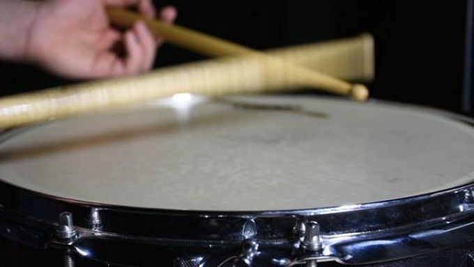 The top of a snare drum with blurry drumsticks rebounding off of it