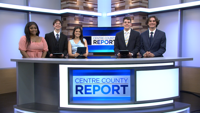 photo of anchors standing behind an anchor desk in a television studio