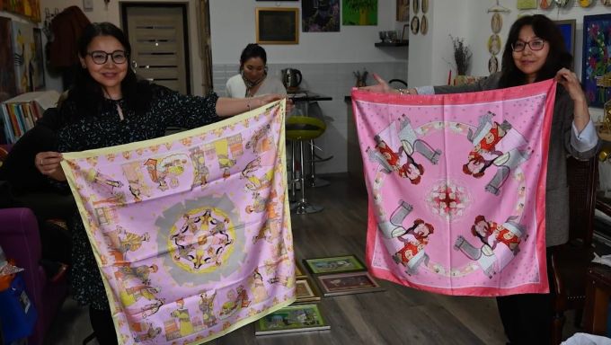 Two women holding their traditional fabrics in Kazakhstan