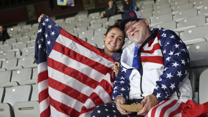 Two seated fans holding a U.S. flag