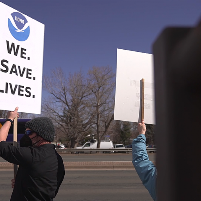 Protesters rally for the National Oceanic and Atmospheric Administration. "We Protect Lives," the sign says.