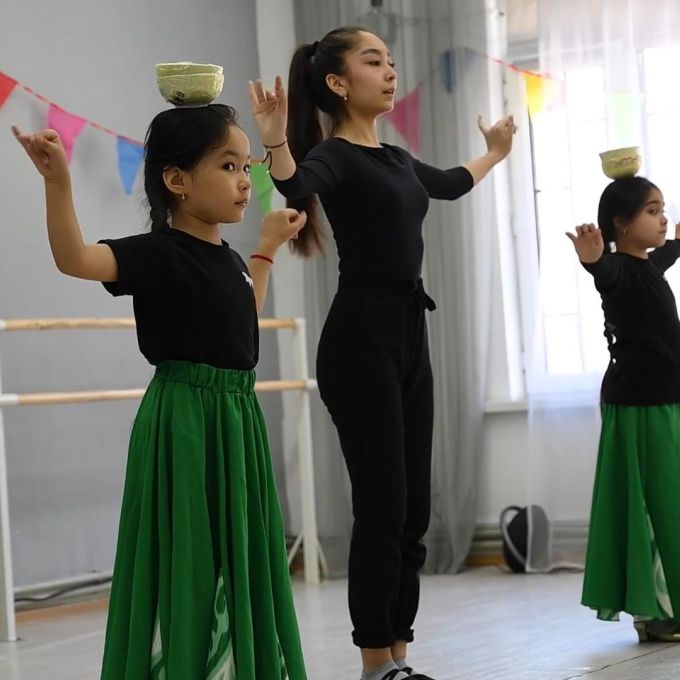 A Uyghur dance instructor teaching two young Uyghur girls how to perform a traditional dance
