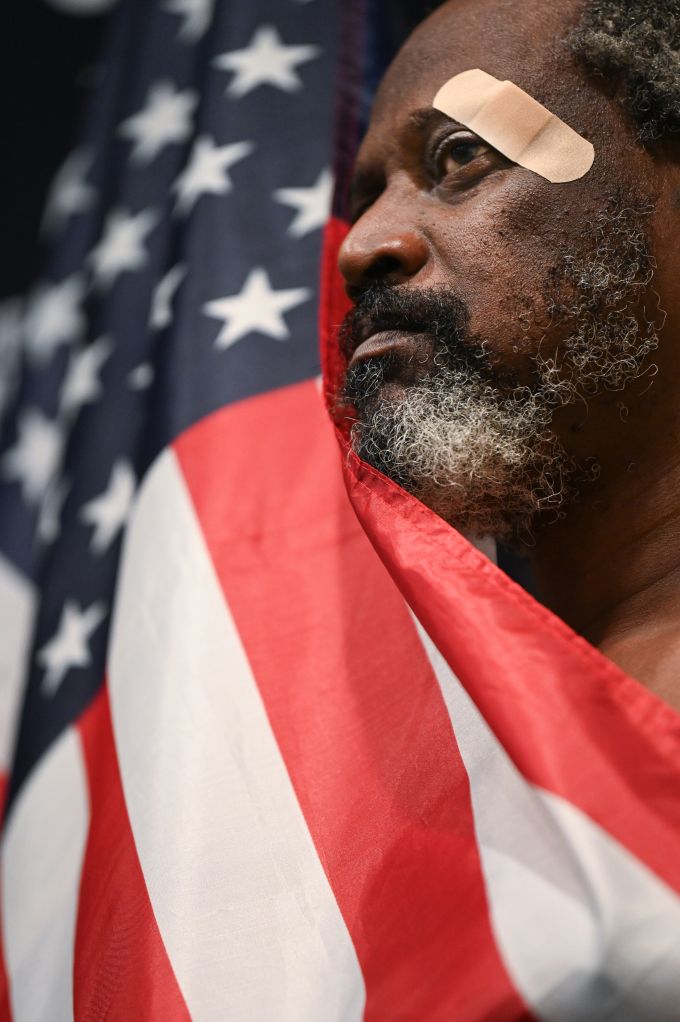 Man with bandage on head and draped in flag