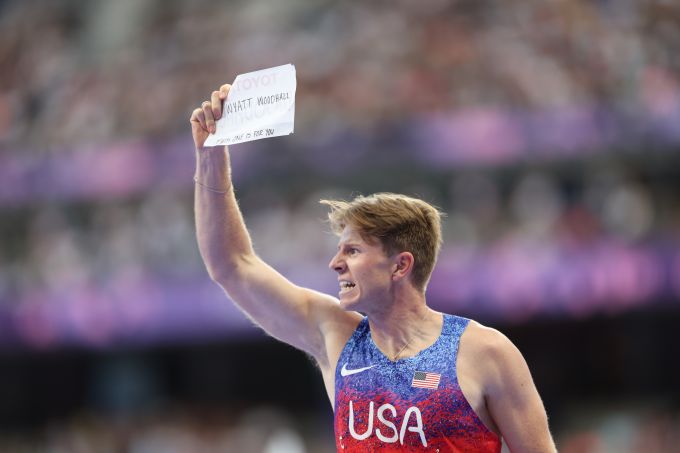 A runner holds his number aloft after a race