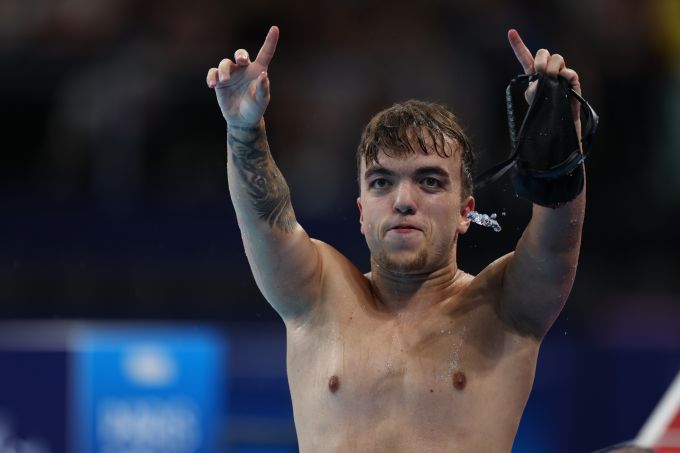 A swimmer raises his arms