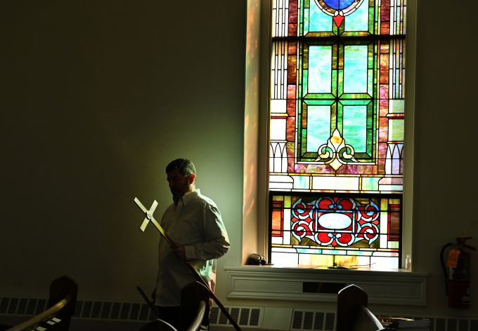 Man in white carrying a cross