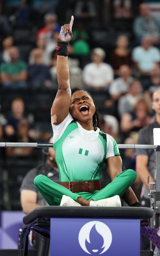 Woman raises her right arm and points toward the sky