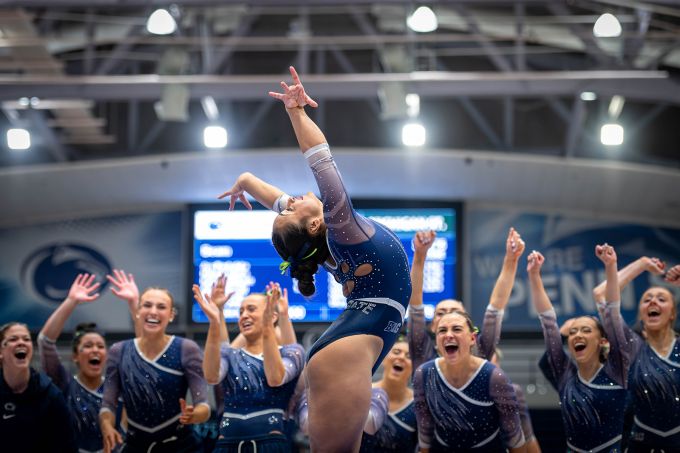 A gymnast in blue soaks in teammates' cheers