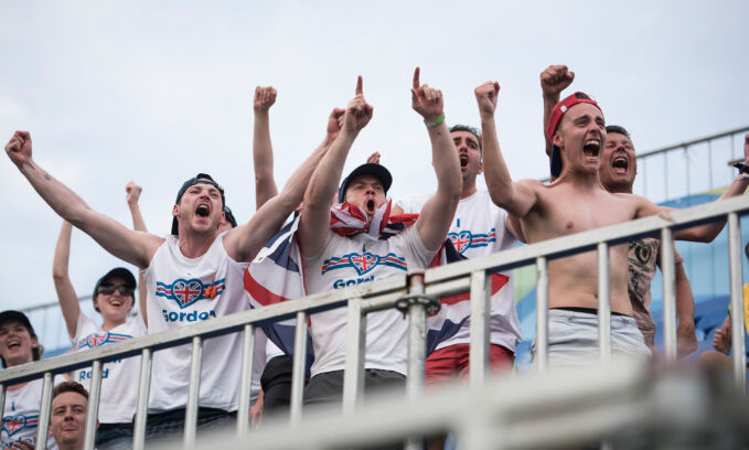 A half dozen fans celebrating with their arms raised