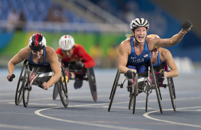 Wheelchair racer raises arm as she crosses finish line