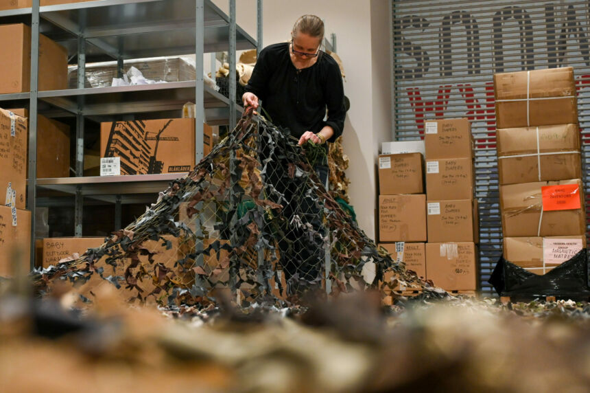 A man in black inspects a camo net